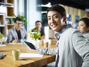 young confident asian businessman turning to look at camera during meeting in office.