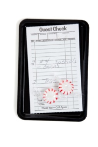 A guest check on a tip tray with mints on a white background